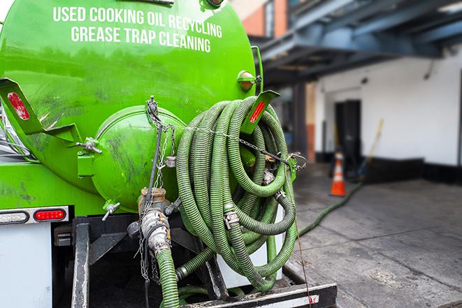 a professional plumber using a pump to empty a grease trap in Albion, MI